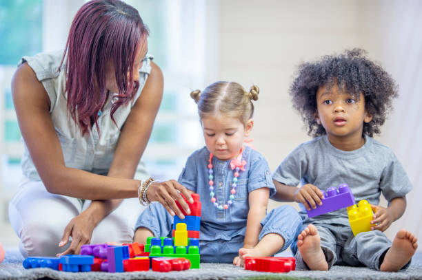 istock Preschool teacher playing with blocks with her students 1302901456
