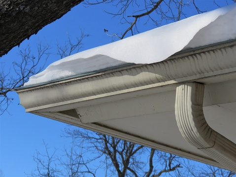 Snow drifting off a roof gutter on a house. Photographed in Texas on February 2021. Close-up