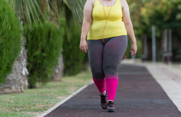 istock Young oversized woman exercising in a public park 1302906618