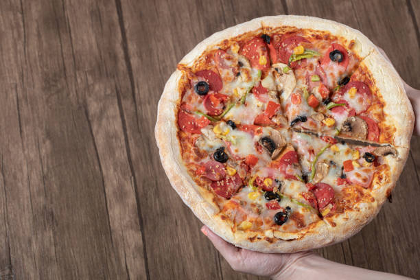 istock Chef or baker holding a big pizza in tomato sauce with black olives 1302906825