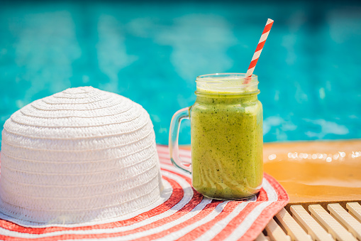 Green smoothies of spinach and banana on the background of the pool. Healthy food, healthy smoothies.