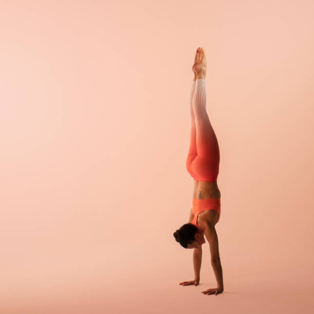 femme athlétique utilisant des sportswear, le pantalon et le dessus, exécutant le handstand dans le yoga - inversion yoga photos et images de collection