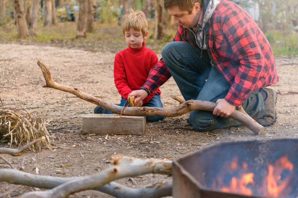 istock Father helping his son to cut a log for a camp fire 1302917026