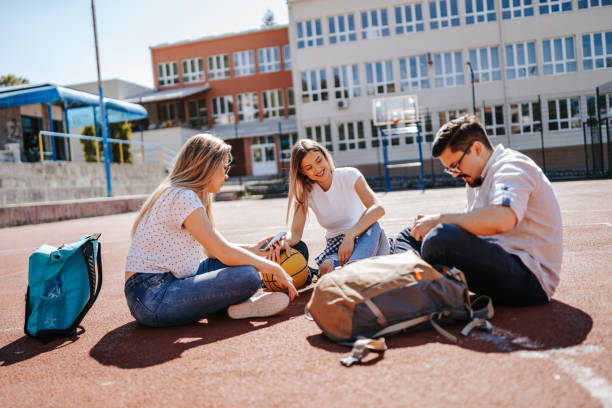 istock Young friends using digital tablet on basketball court, discussing strategy before the game 1302918058