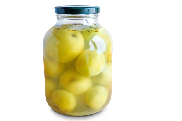 Home canning: in a large glass jar pickled apples. Presented on a white background.
