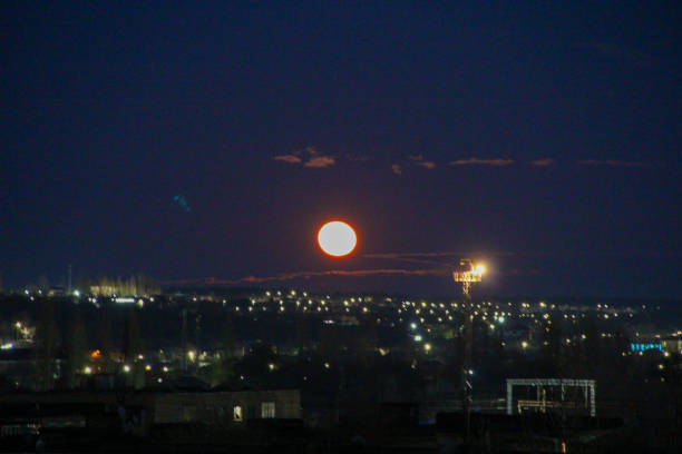 istock Big yellow moon over night city 1302929207