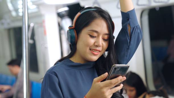istock Young woman using mobile phone on public train 1302930315