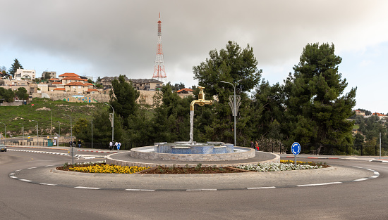 Zefat, Israel, February 13, 2021 : A fountain in the form of a faucet with water flowing out of it stands at a roundabout in the city of Zefat, in northern Israel
