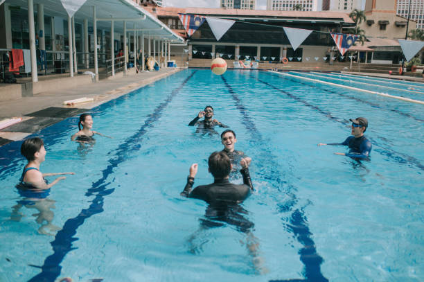 match leisure game asian multi ethic group of men having fun splashing playing ball in swimming pool