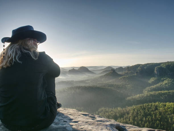 istock Pretty Hiker Backpacker Sitting On The Peak Edge And Enjoying Mountains View Valley During Mist 1302935252