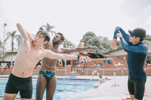 asian men learning swimming skill from fitness instructor at poolside arm outstretch