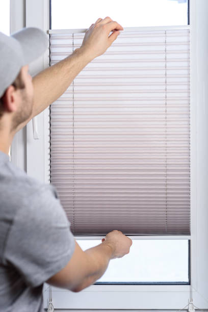 istock Man installing gray pleated blinds on the window 1302938956