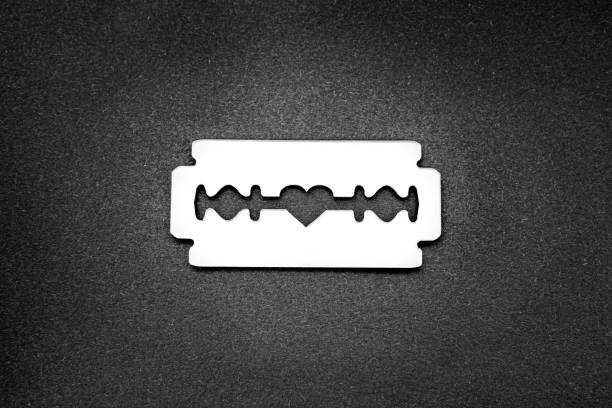 Mirror surface razor blade with a heart-shaped opening in the middle on a black backdrop Razor blade with a heart-shaped opening in the middle razor blade stock pictures, royalty-free photos & images