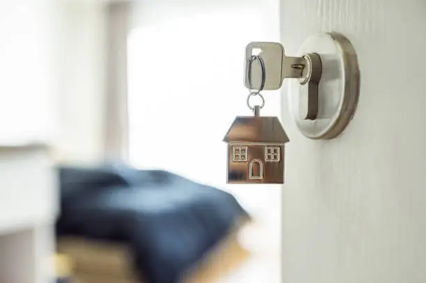 Photo of Open the door and door handle with a key and a keychain shaped house. Property investment and house mortgage financial real estate concept