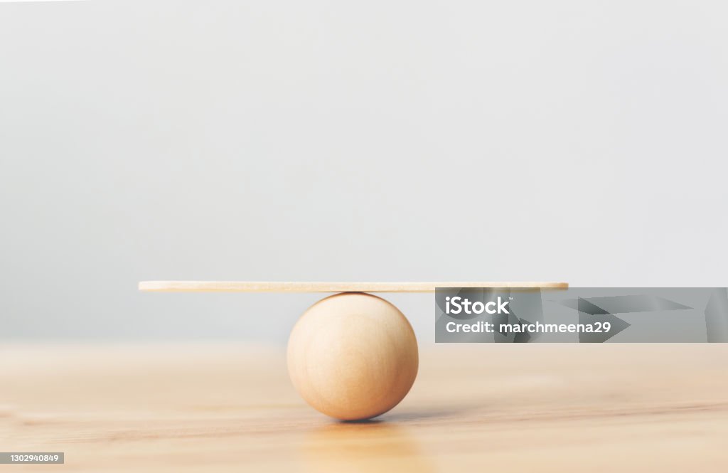 Wooden seesaw scale empty balancing on wooden sphere on wood table Balance Stock Photo