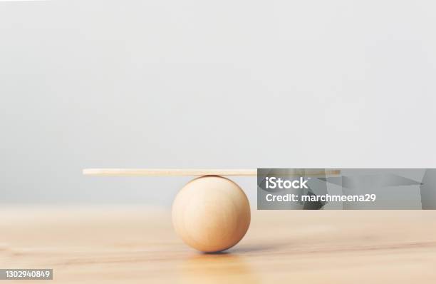 Wooden Seesaw Scale Empty Balancing On Wooden Sphere On Wood Table Stock Photo - Download Image Now