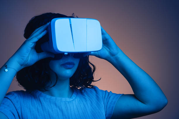 istock young woman adjusting virtual reality glasses. interior artificial light of cold and warm color. futuristic video game environment. activities at home 1302941622