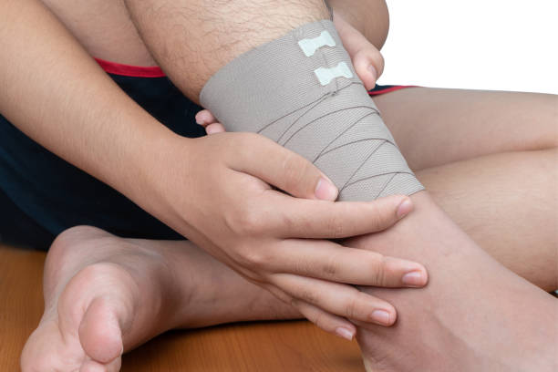 Wounded foot cover with elastic bandage. Close-up of young man with bandaging on his foot. stock photo