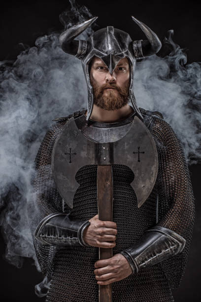 Weapon wielding fantasy warrior wearing a horned helmet in studio shot