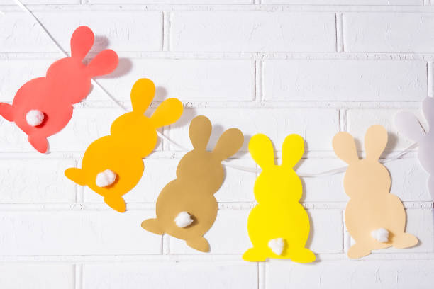 istock Paper Easter bunnies garland. Easter rabbits garland on a stone brick wall. 1302942065