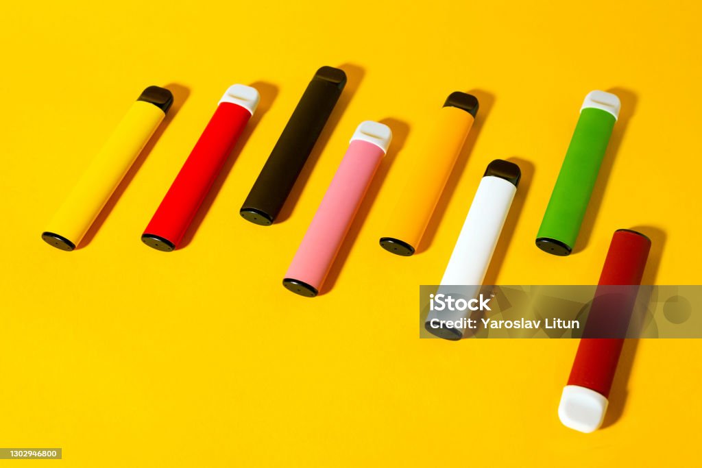 Layout of colorful disposable electronic cigarettes with shadows on a yellow background. The concept of modern smoking, vaping and nicotine. Top view Layout of colorful disposable electronic cigarettes with shadows on a yellow background. The concept of modern smoking, vaping and nicotine. Top view. Electronic Cigarette Stock Photo