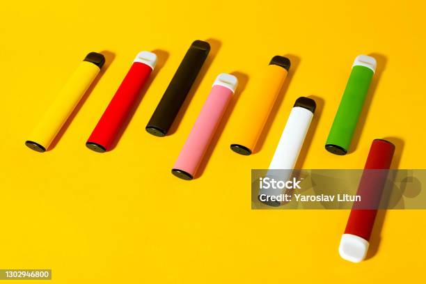 Layout Of Colorful Disposable Electronic Cigarettes With Shadows On A Yellow Background The Concept Of Modern Smoking Vaping And Nicotine Top View Stock Photo - Download Image Now