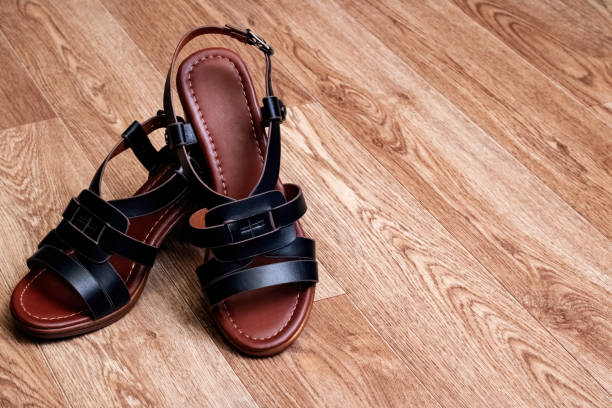 istock Women's sandals with straps on wooden background 1302949999