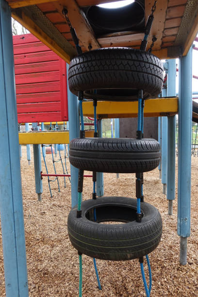 parque infantil em um parque público pneus verticalmente alinhados - tire swing - fotografias e filmes do acervo