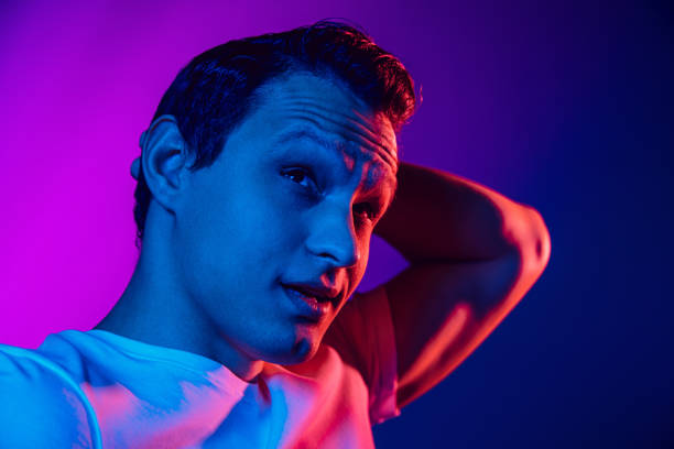 istock Caucasian man's portrait isolated on purple blue studio background in multicolored neon light 1302951218
