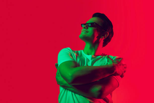 Caucasian man's portrait isolated on red studio background in multicolored neon light