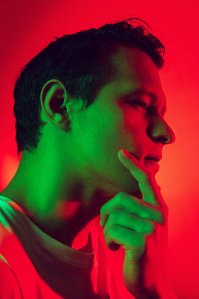istock Caucasian man's portrait isolated on red studio background in multicolored neon light 1302951258