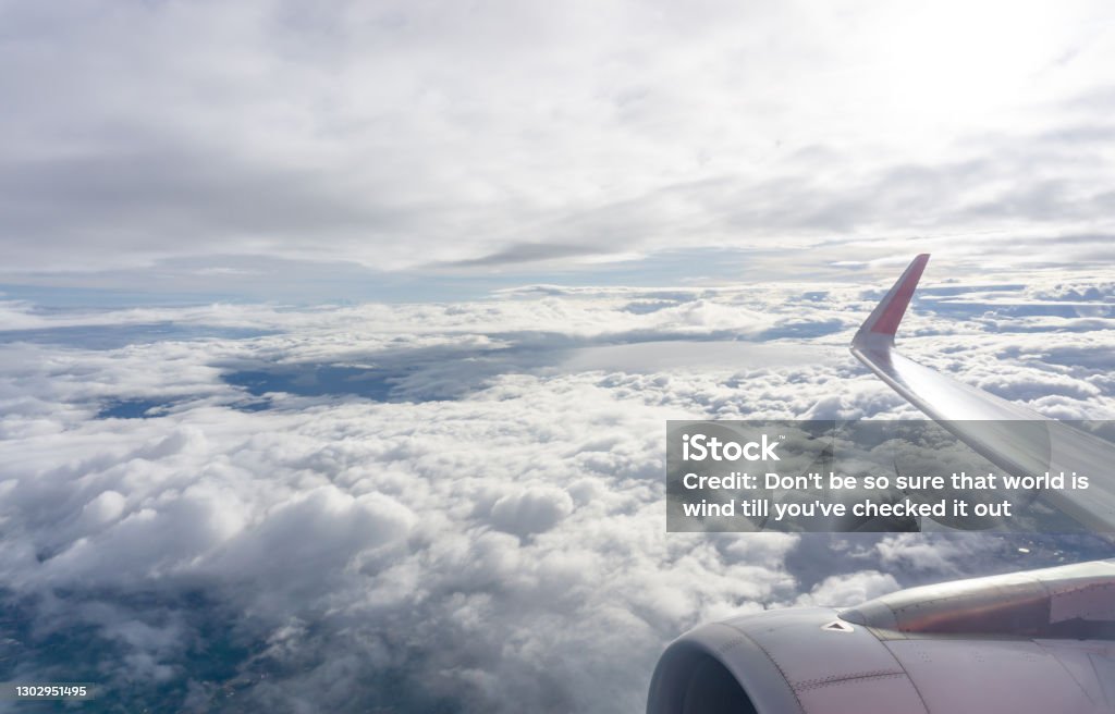 Sky scape view from clear glass window seat to the aircraft wing of the air plane, traveling on white fluffy clouds and vivid blue sky Air Vehicle Stock Photo