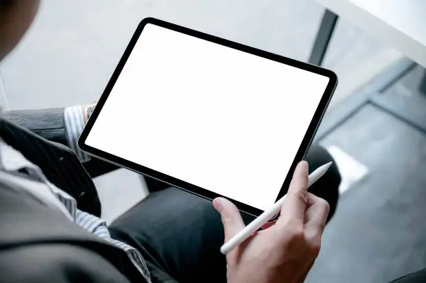 Photo of Closeup image of businessman hand holding digital table with blank screen while sitting at office.