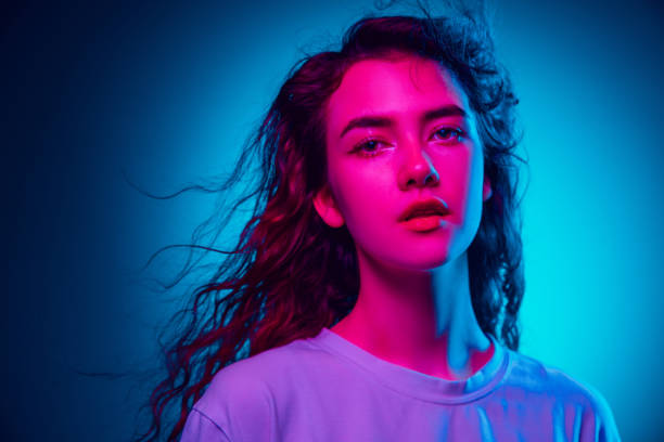 istock Caucasian woman's portrait isolated on blue studio background in multicolored neon light 1302953761