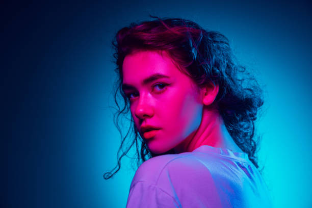 istock Caucasian woman's portrait isolated on blue studio background in multicolored neon light 1302953771