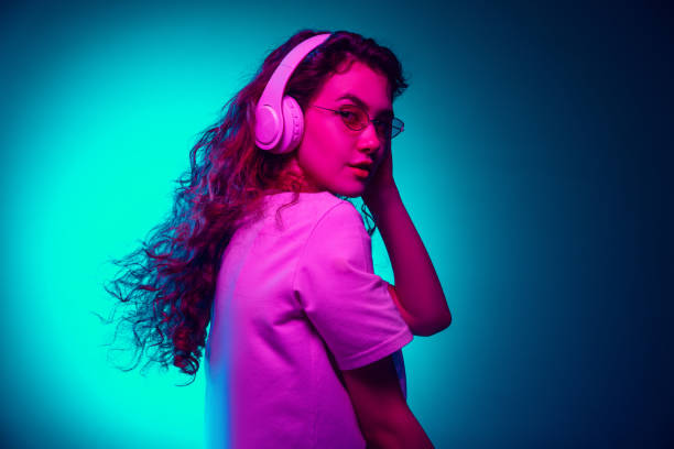 istock Caucasian woman's portrait isolated on blue studio background in multicolored neon light 1302953794