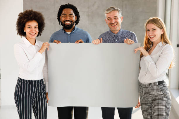 istock Happy business team with an empty placard in the office. 1302955269