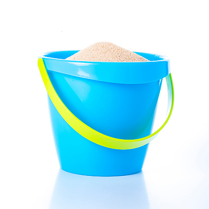 Front view of a blue sand bucket full of sand isolated on white background. The sand bucket has a light green handle Studio shot taken with Canon EOS 6D Mark II and Canon EF 100 mm f/ 2.8