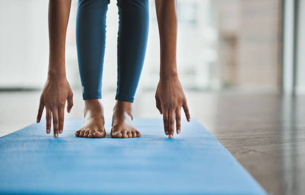 Good health is well within your reach Shot of an unrecognisable woman practicing a yoga routine at home touching toes stock pictures, royalty-free photos & images