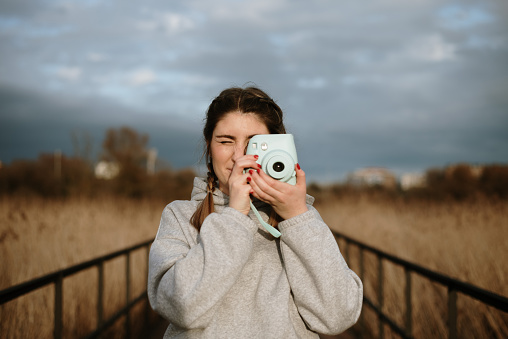 A young woman using a blue instant camera