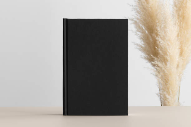 istock Black book mockup with pampas decoration on a beige table. 1302958467