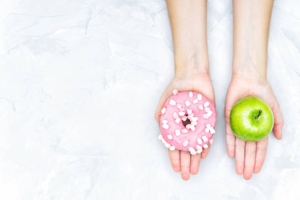 istock Female hands offering to choose between an apple and a doughnut 1302960055