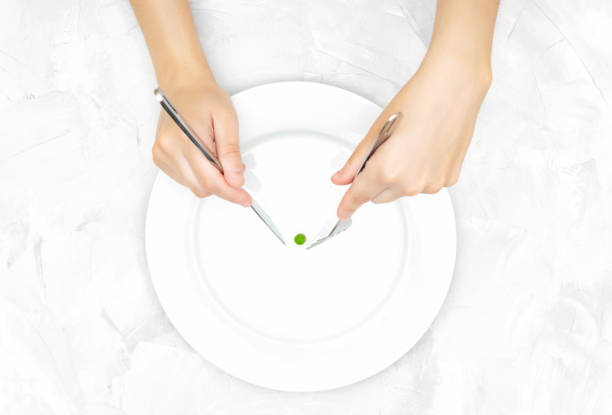 istock Female catching a single pea on a plate with knife and fork 1302960103