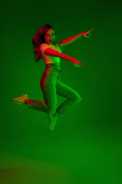 istock Caucasian woman's portrait isolated on green studio background in multicolored neon light 1302961015