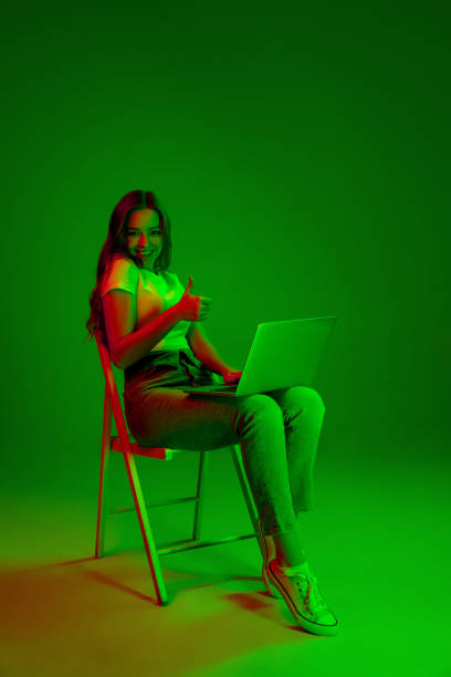 istock Caucasian woman's portrait isolated on green studio background in multicolored neon light 1302961017