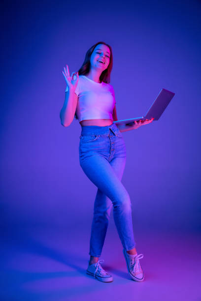 istock Caucasian woman's portrait isolated on blue studio background in multicolored neon light 1302961018