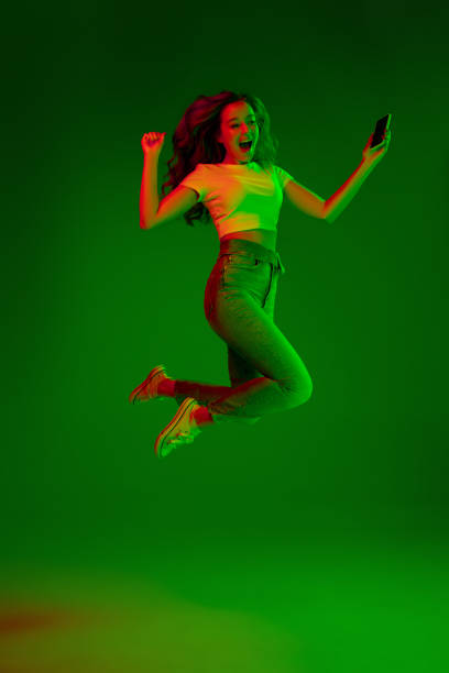 istock Caucasian woman's portrait isolated on green studio background in multicolored neon light 1302961020