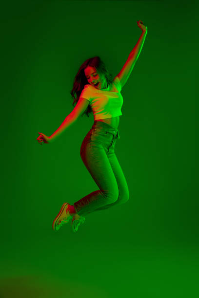 Caucasian woman's portrait isolated on green studio background in multicolored neon light