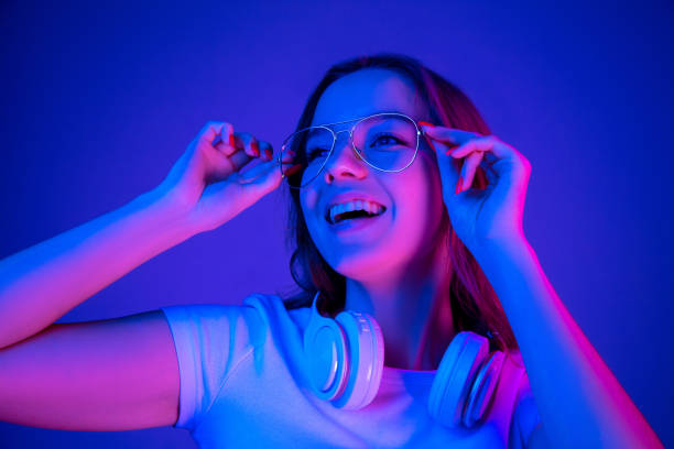 istock Caucasian woman's portrait isolated on blue studio background in multicolored neon light 1302961035