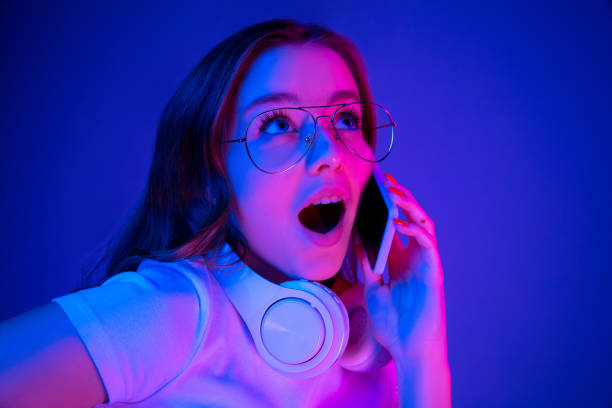 istock Caucasian woman's portrait isolated on blue studio background in multicolored neon light 1302961039